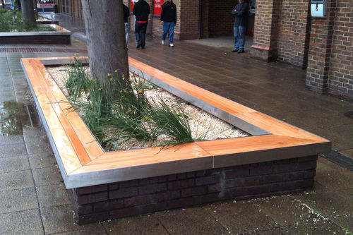 Moderne Bank für den öffentlichen Raum - HOWARD CENTRE, BEDFORD - Factory Street Furniture - Holz / Edelstahl / mit integrierten Pflanzkübeln
